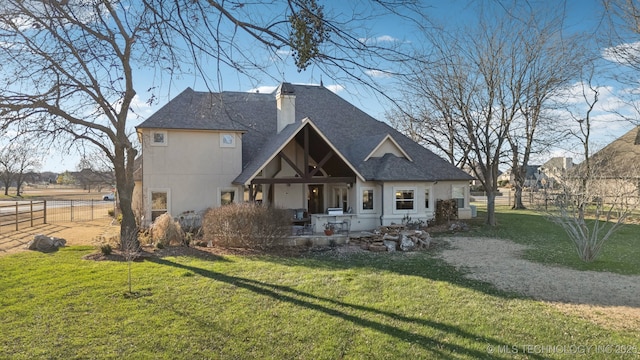 back of property with a yard, a chimney, and fence