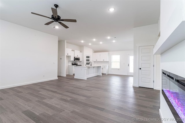 unfurnished living room with dark hardwood / wood-style flooring, ceiling fan, and sink