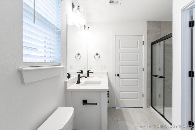 bathroom with tile patterned floors, vanity, a shower with shower door, and toilet