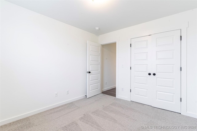 unfurnished bedroom featuring light carpet and a closet