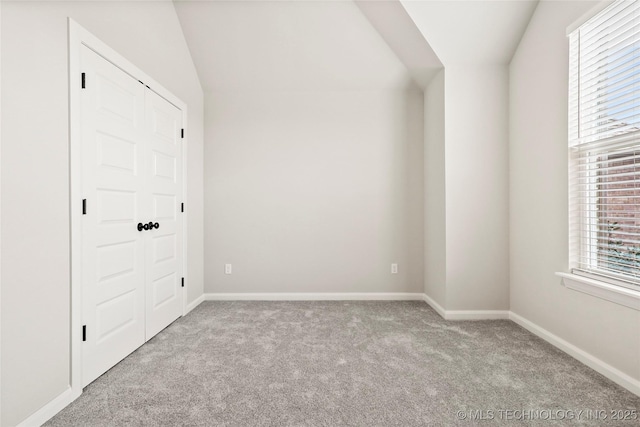 empty room featuring light colored carpet and vaulted ceiling