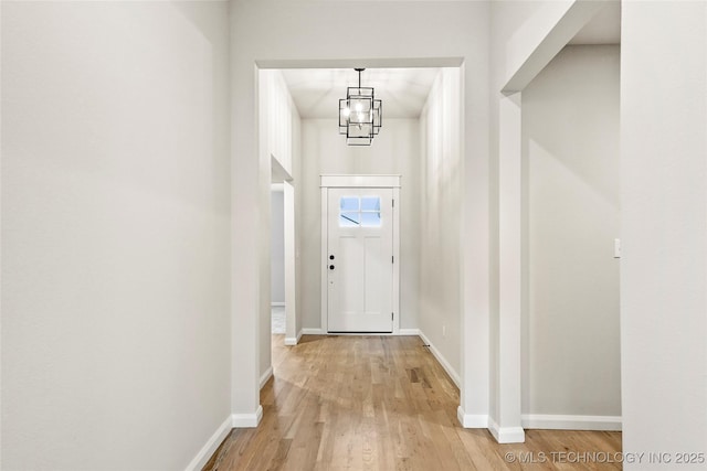 doorway to outside featuring a notable chandelier and light hardwood / wood-style flooring