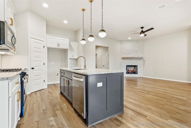 kitchen with white cabinetry, sink, an island with sink, decorative light fixtures, and appliances with stainless steel finishes