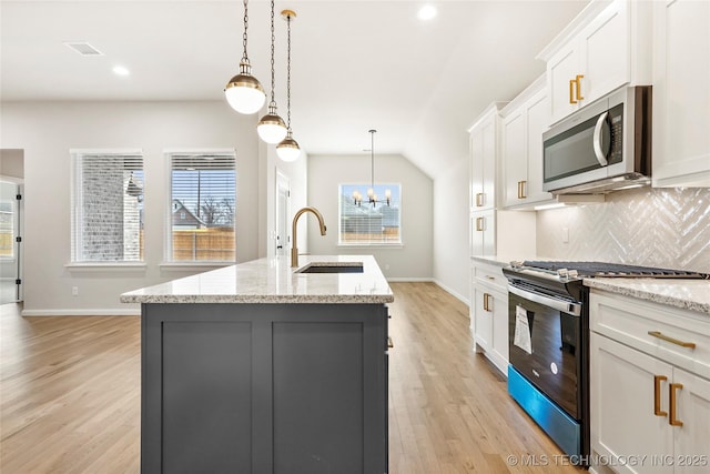 kitchen with white cabinets, black range with gas stovetop, sink, and a kitchen island with sink