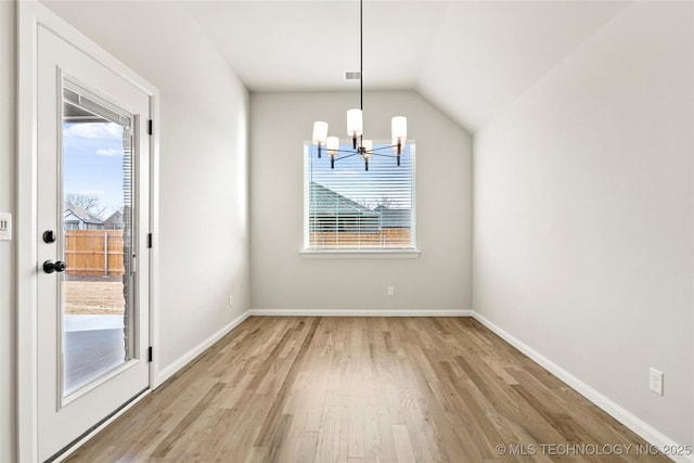 unfurnished dining area featuring light wood-type flooring, lofted ceiling, and a notable chandelier