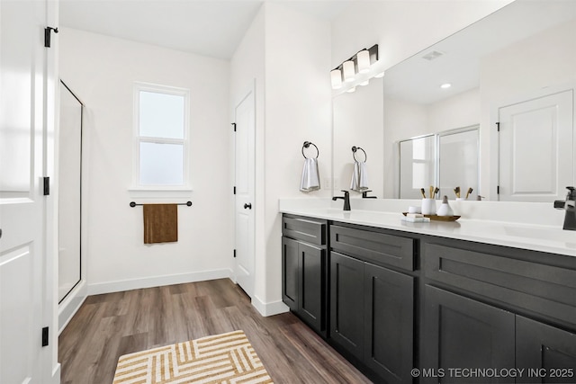 bathroom featuring hardwood / wood-style flooring, vanity, and walk in shower