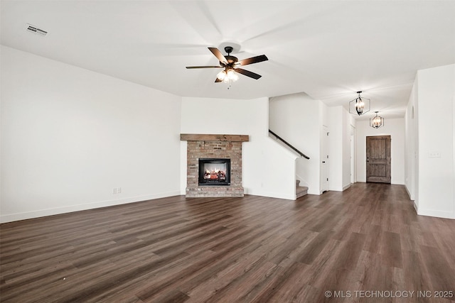 unfurnished living room with a fireplace, dark hardwood / wood-style flooring, and ceiling fan with notable chandelier