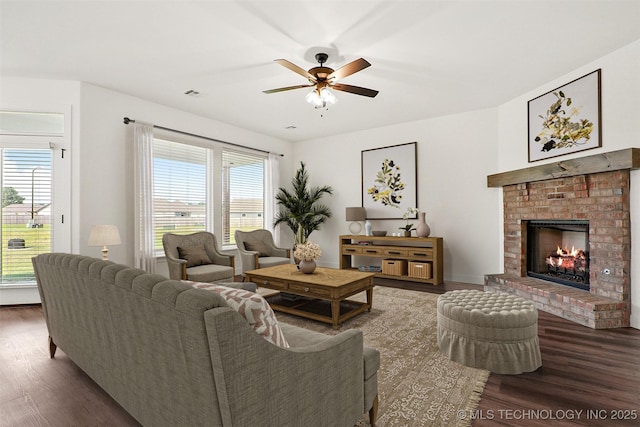 living room featuring ceiling fan, dark wood-type flooring, and a brick fireplace