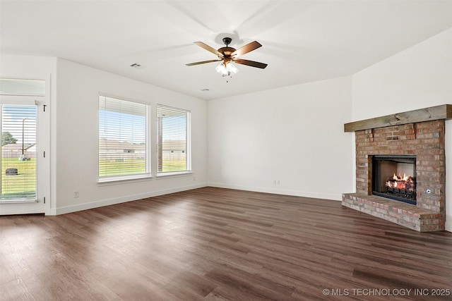 unfurnished living room with plenty of natural light, ceiling fan, dark hardwood / wood-style flooring, and a brick fireplace