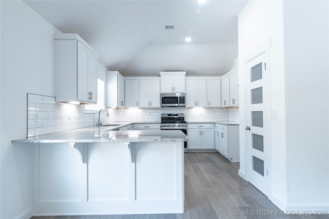 kitchen featuring kitchen peninsula, appliances with stainless steel finishes, sink, white cabinetry, and lofted ceiling