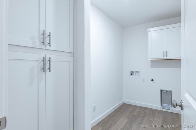 clothes washing area featuring electric dryer hookup, hookup for a washing machine, cabinets, and light hardwood / wood-style floors