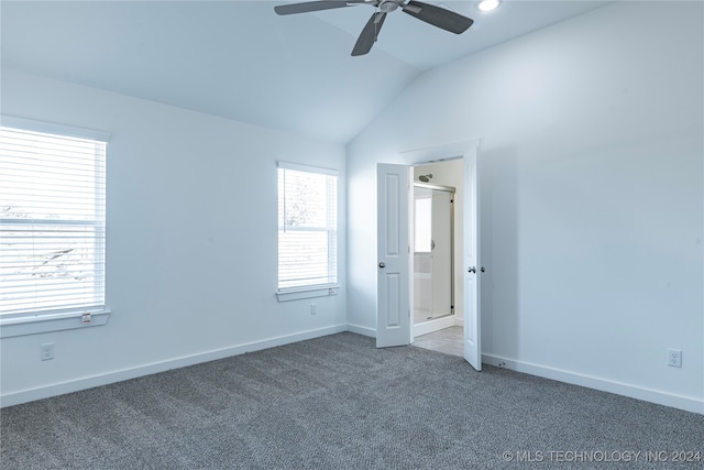 unfurnished bedroom with ensuite bath, ceiling fan, dark carpet, and vaulted ceiling