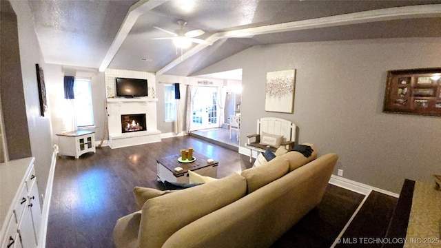 living room featuring lofted ceiling with beams, ceiling fan, dark wood-type flooring, and a fireplace