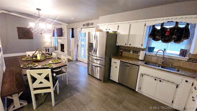 kitchen with sink, hanging light fixtures, stainless steel appliances, decorative backsplash, and white cabinets