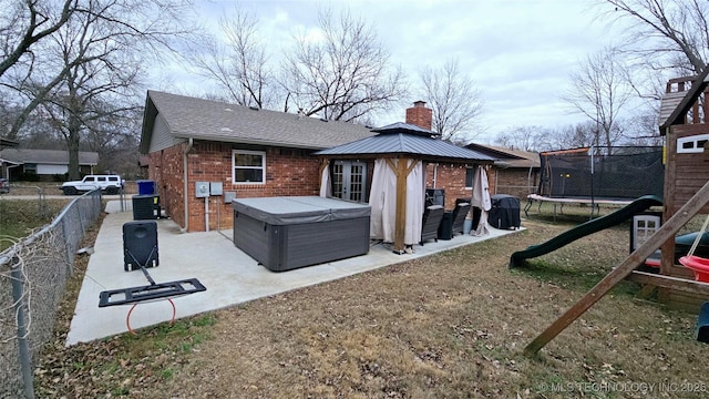 back of house featuring a trampoline, cooling unit, a patio, a hot tub, and a playground