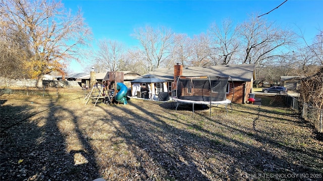 rear view of house featuring a playground and a trampoline