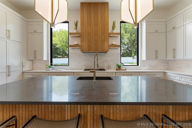 kitchen featuring a breakfast bar, a wealth of natural light, white cabinets, and tasteful backsplash