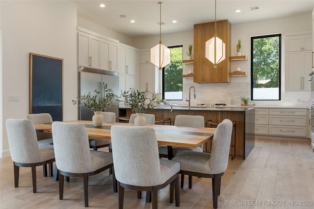 dining area featuring light hardwood / wood-style flooring, a healthy amount of sunlight, and sink