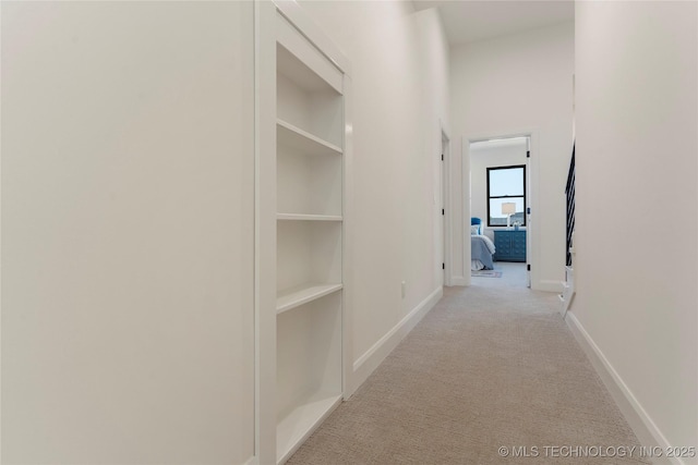 corridor featuring built in shelves and light carpet