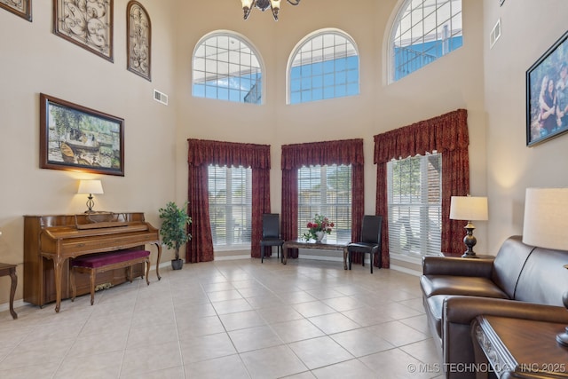 tiled living room featuring a high ceiling, a healthy amount of sunlight, and a notable chandelier