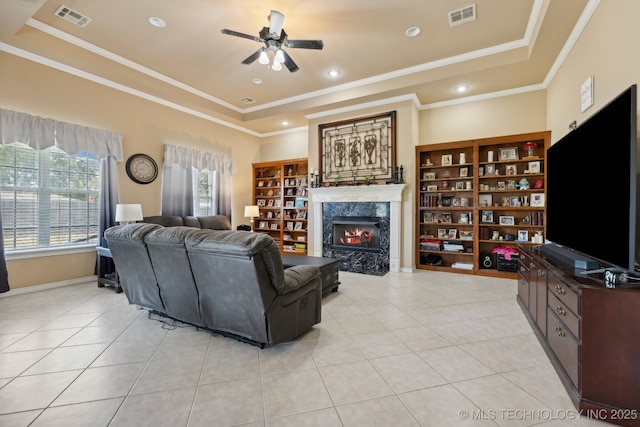 living room with light tile patterned flooring, a premium fireplace, and a tray ceiling