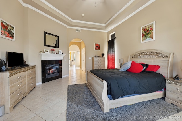 tiled bedroom with ornamental molding, a high ceiling, and a tile fireplace