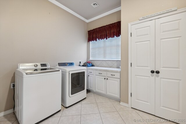 laundry room with cabinets, light tile patterned floors, ornamental molding, and washing machine and clothes dryer