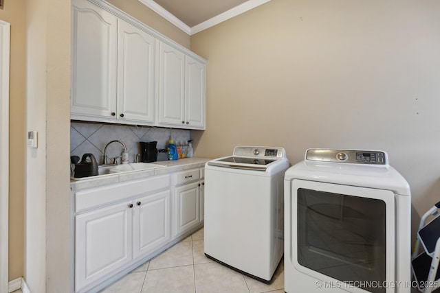 clothes washing area featuring cabinets, crown molding, sink, washing machine and clothes dryer, and light tile patterned flooring