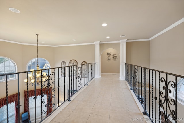 corridor featuring decorative columns, light tile patterned flooring, a chandelier, and ornamental molding