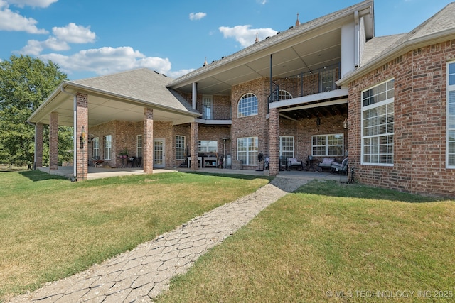 rear view of house featuring a yard, a balcony, and a patio