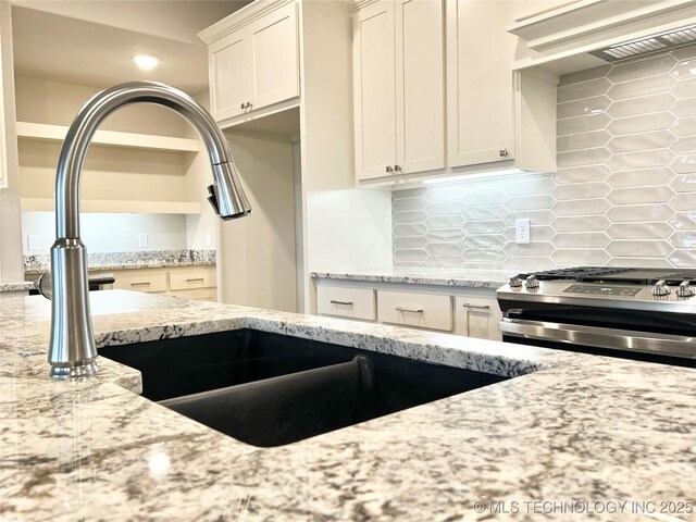 kitchen featuring premium range hood, decorative backsplash, stainless steel range with gas cooktop, and light stone counters