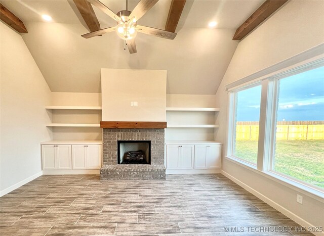 unfurnished living room with lofted ceiling with beams, a brick fireplace, and ceiling fan