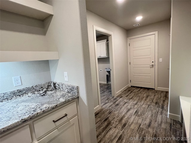 interior space featuring white cabinetry and light stone counters