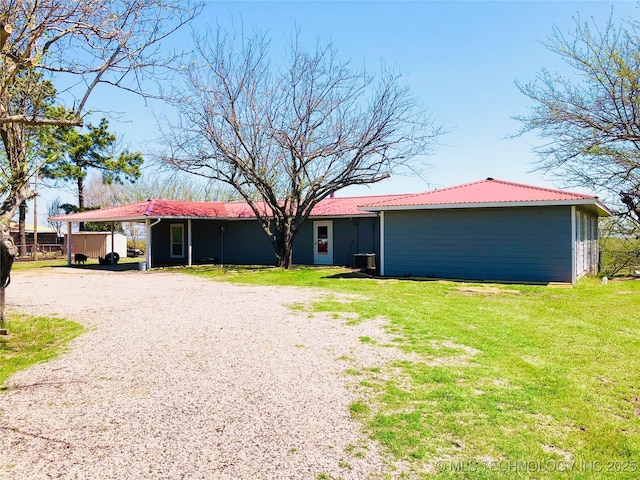 back of house featuring a carport, cooling unit, and a lawn