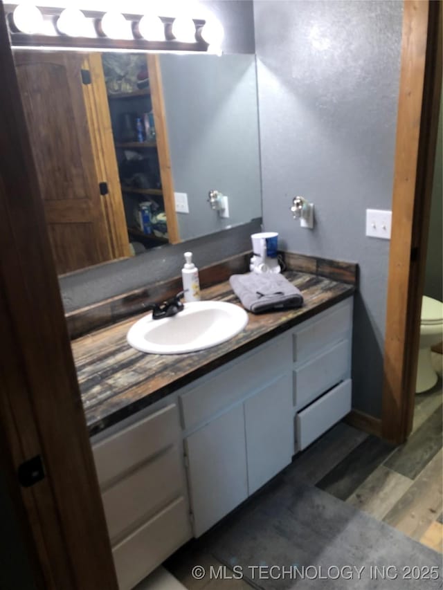 bathroom featuring hardwood / wood-style flooring, vanity, and toilet