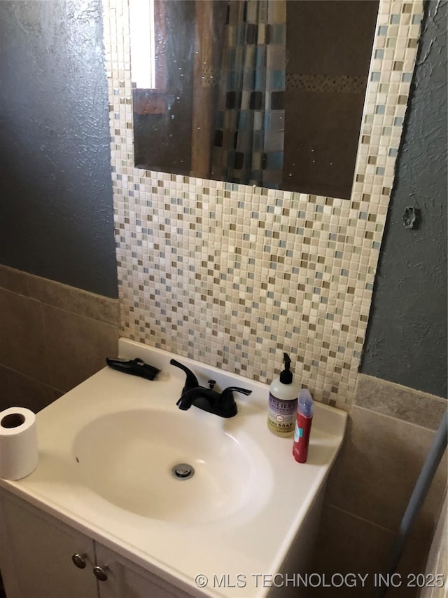 bathroom featuring vanity, backsplash, and tile walls