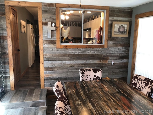 interior space with white refrigerator and wooden walls