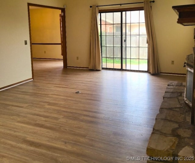 unfurnished room featuring a stone fireplace and hardwood / wood-style flooring