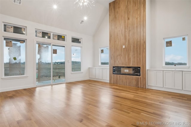 unfurnished living room with heating unit, high vaulted ceiling, and light hardwood / wood-style flooring