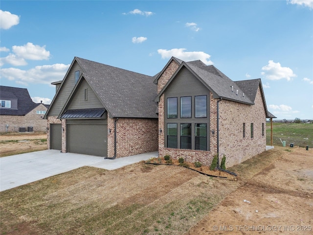 view of front facade featuring an attached garage, driveway, brick siding, and roof with shingles