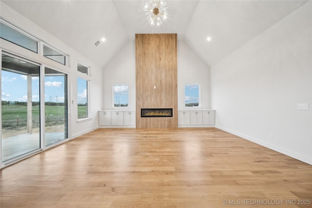 unfurnished living room featuring high vaulted ceiling, light wood-style flooring, a chandelier, a fireplace, and recessed lighting