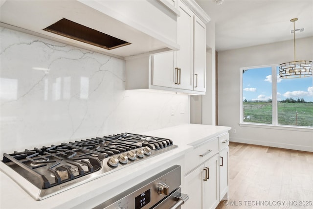 kitchen featuring stainless steel gas stovetop, light wood finished floors, backsplash, white cabinetry, and visible vents