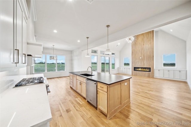 kitchen featuring a sink, open floor plan, light brown cabinetry, light wood-style flooring, and appliances with stainless steel finishes