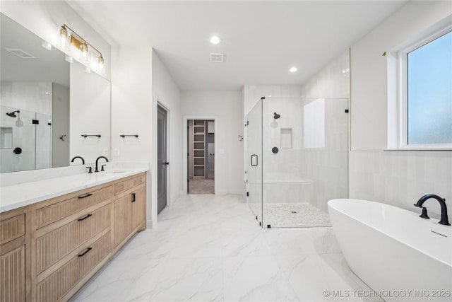 full bath featuring a shower stall, a walk in closet, vanity, marble finish floor, and a freestanding bath