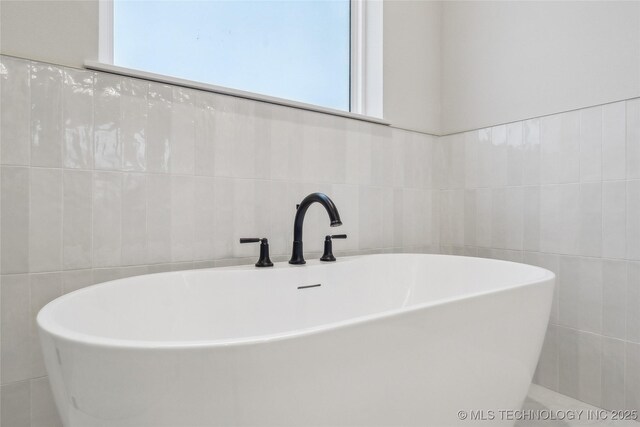 bathroom featuring tile walls and a freestanding tub