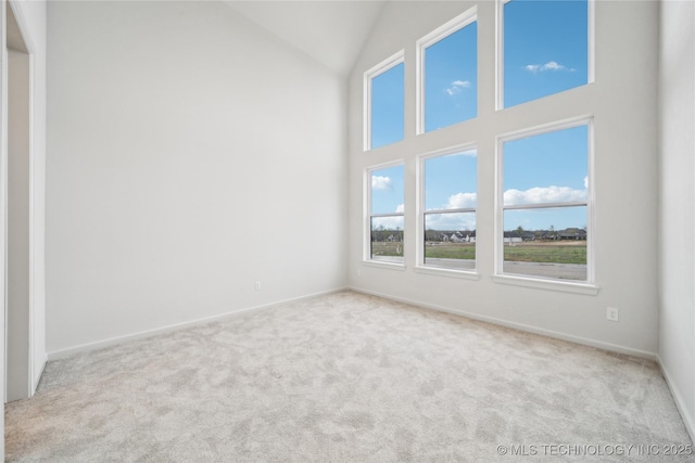 carpeted empty room with high vaulted ceiling and baseboards