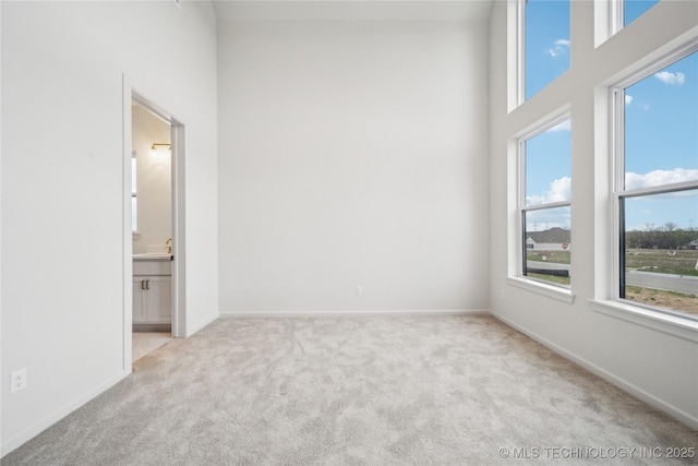 unfurnished room featuring carpet floors, a high ceiling, baseboards, and plenty of natural light