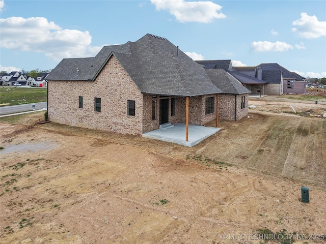 back of property with brick siding and a patio area