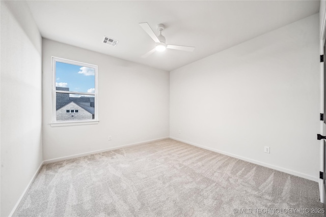 empty room with ceiling fan, carpet floors, visible vents, and baseboards