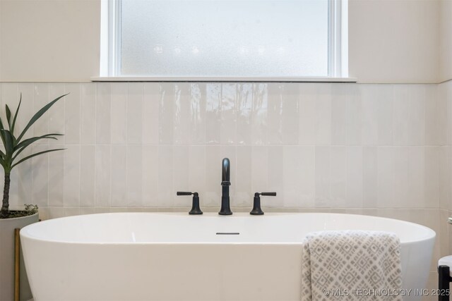 2509 E 134th Cir, Bixby, OK 74008 - bathroom with tile walls, a freestanding tub, and healthy amount of natural light